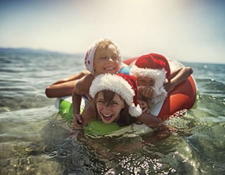 Kids at the beach in Santa hats